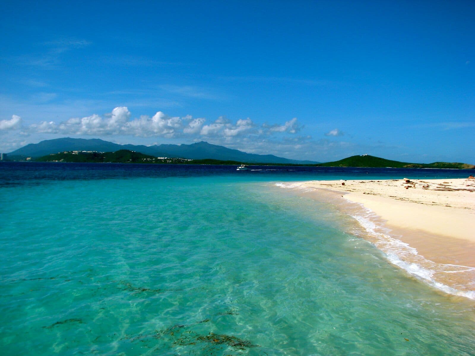 Clear turquoise water and a white sandbar at Cayo Icacos, looking back to the Fajardo coast and El Yunque