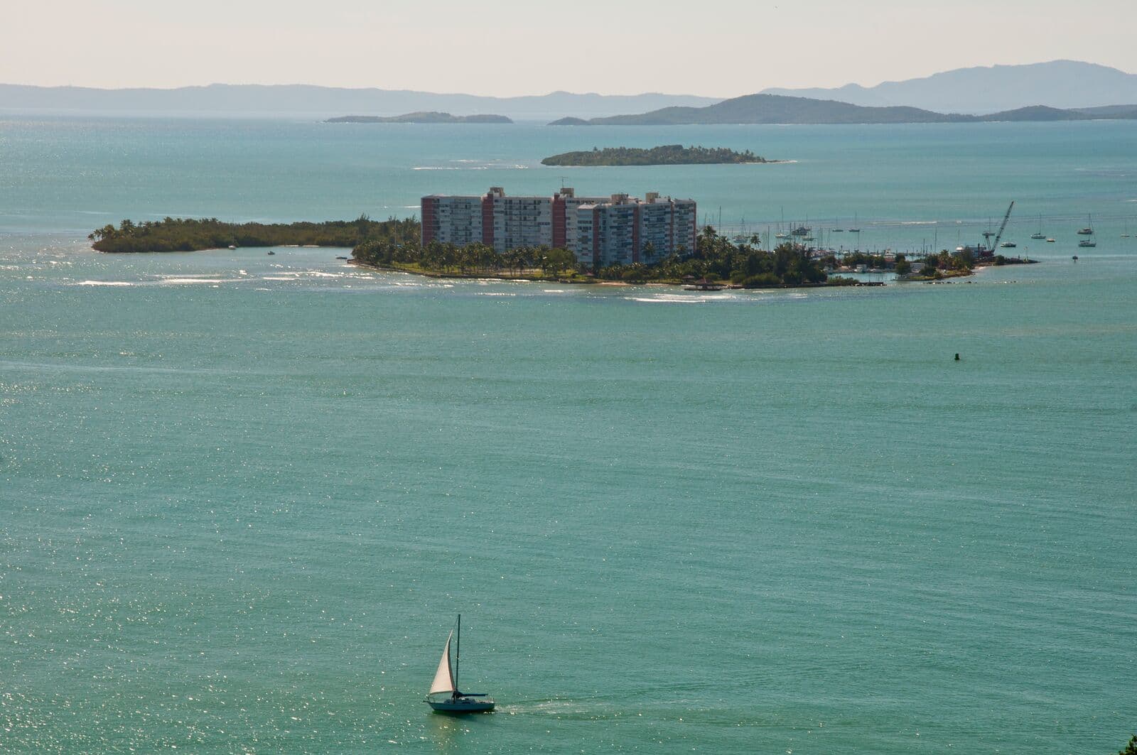 A sailboat crosses the bay at Fajardo toward the condominium towers on Isleta Marina, with offshore cays on the horizon