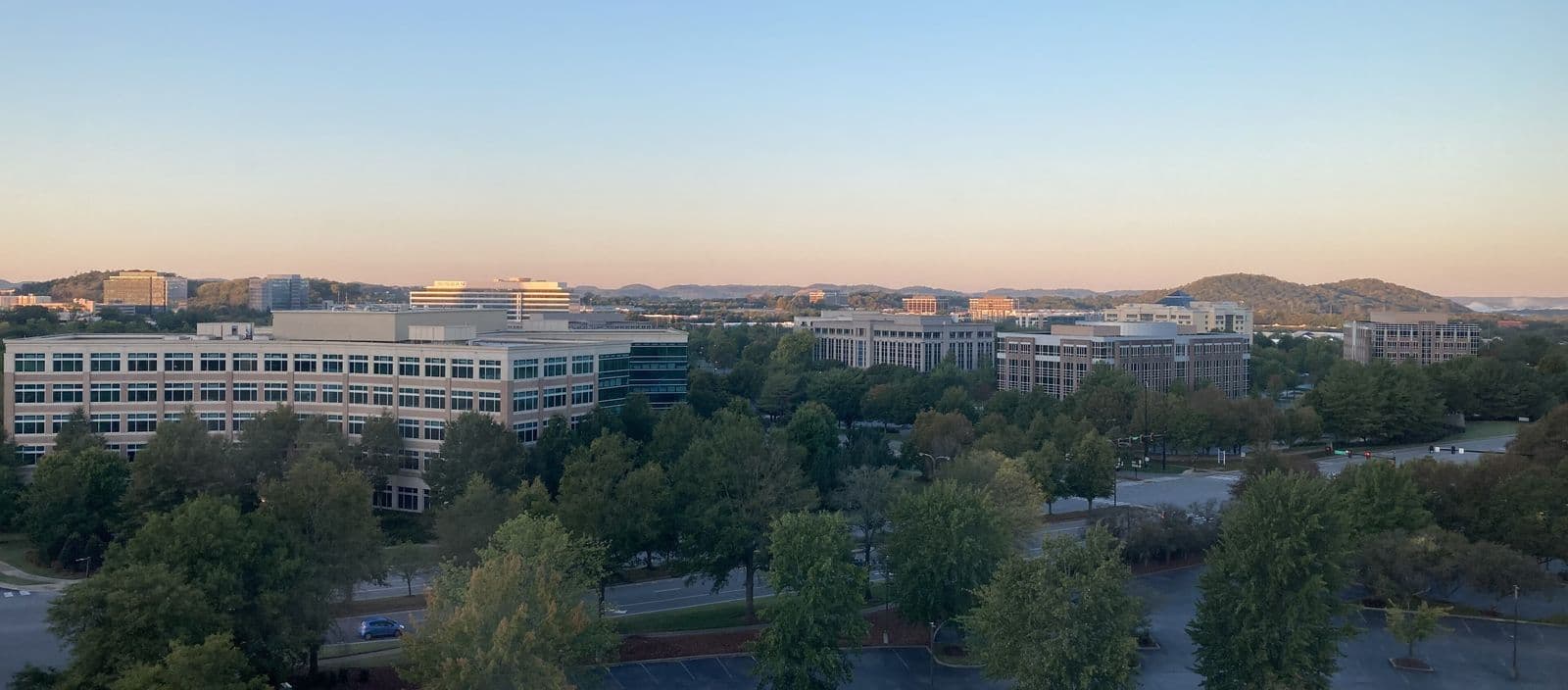 Office buildings of the Cool Springs business district in Franklin at dawn, among green trees with hills on the horizon
