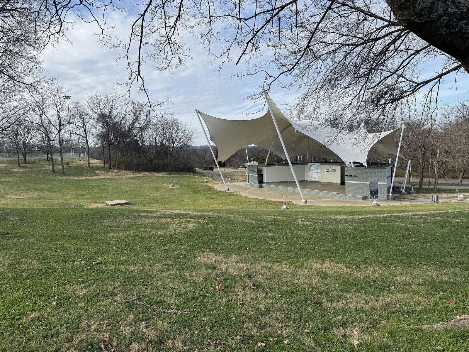 The white tensile roof of the Eddy Arnold Amphitheater above a sloping lawn in Crockett Park, Brentwood, under a blue winter sky