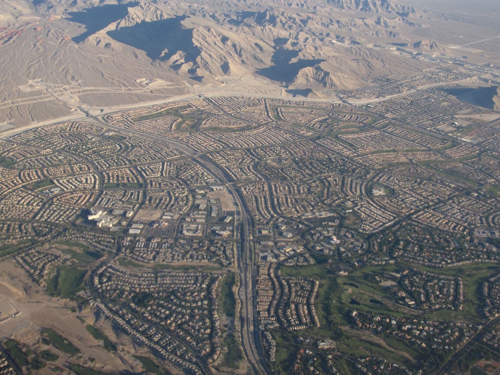 Summerlin from the air: curving streets of desert-toned homes and golf-course greenbelts running up to the bare foothills of the Spring Mountains, with the 215 Beltway threading through