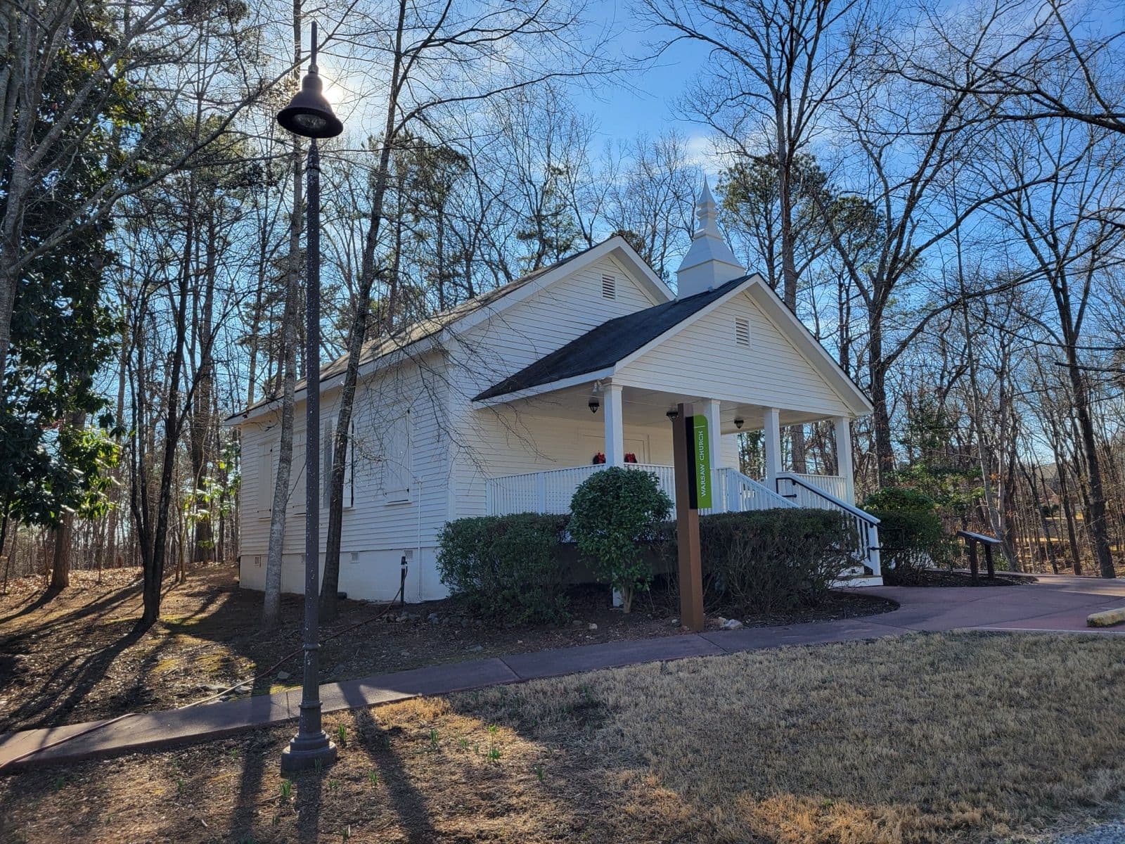 The small white Warsaw Church with its steeple and porch among tall trees at Autrey Mill Nature Preserve