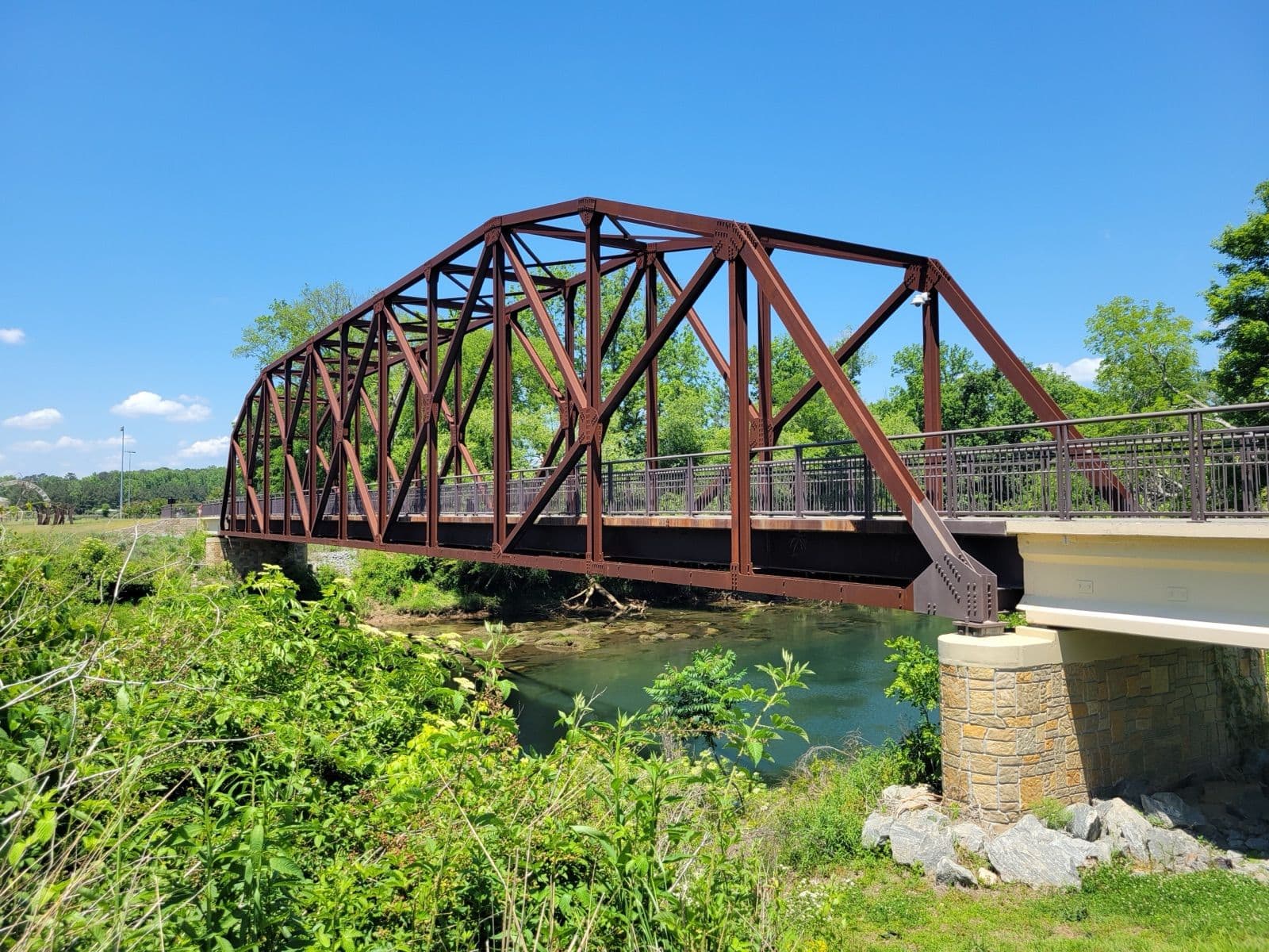 The rust-red steel truss of Rogers Bridge, a footbridge over the Chattahoochee River between Johns Creek and Duluth