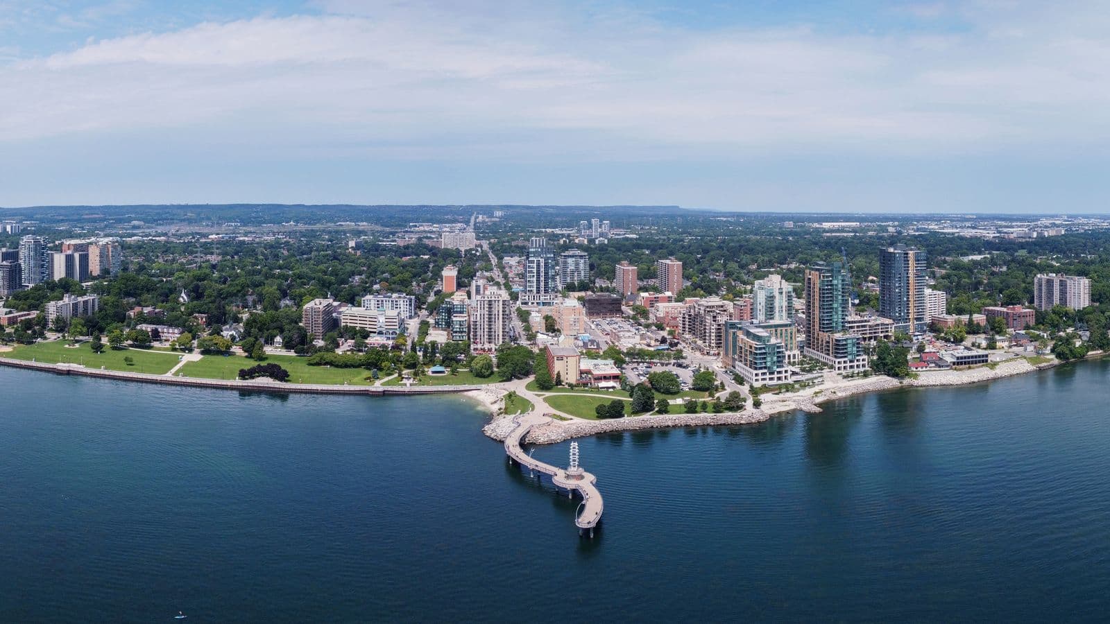 Aerial view of downtown Burlington on Lake Ontario, with the curving Brant Street Pier, the lawns of Spencer Smith Park, apartment towers and the Niagara Escarpment ridge on the horizon