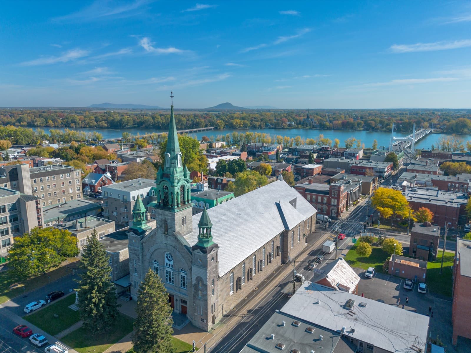 The stone Cathédrale Saint-Jean-l’Évangéliste with its green copper spire above the brick streets of Old Saint-Jean, the Richelieu River beyond