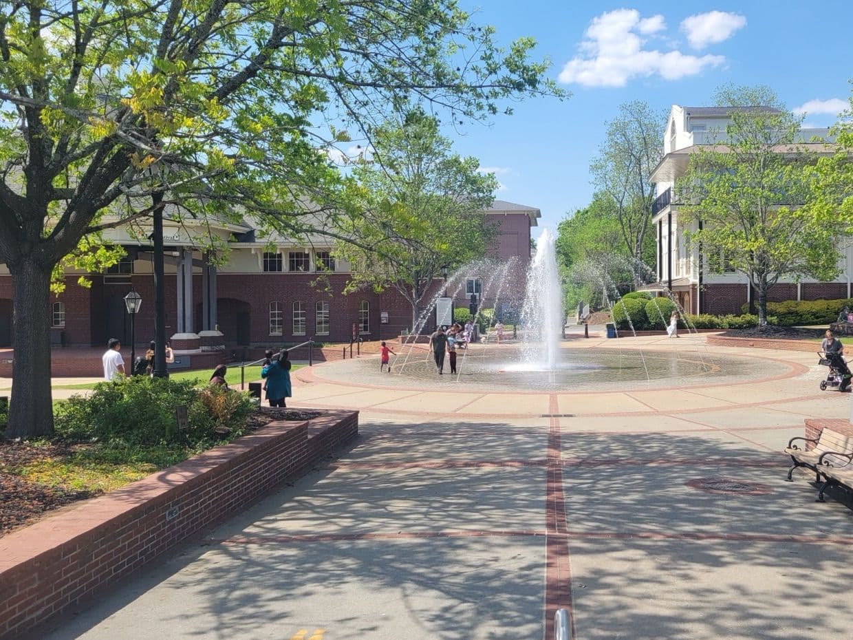 The splash fountain on the Duluth Town Green plaza, with spring trees, the Festival Center and brick buildings around it