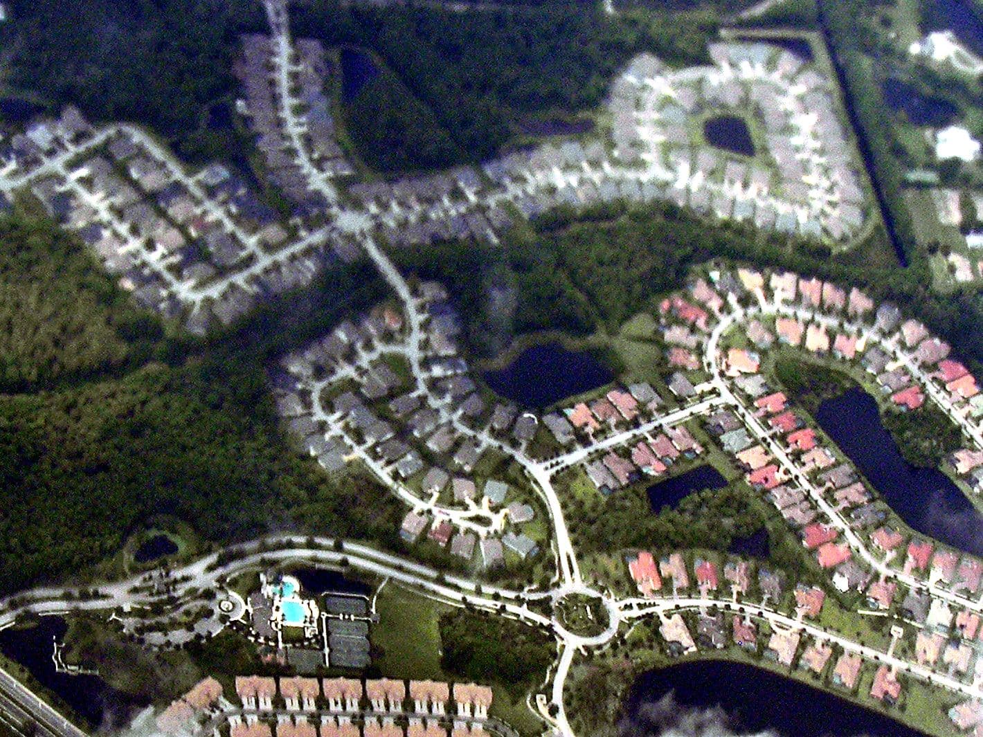 Westchase from the air: curving streets of tile-roofed homes around ponds and woods, with a neighborhood pool, tennis courts and a traffic circle